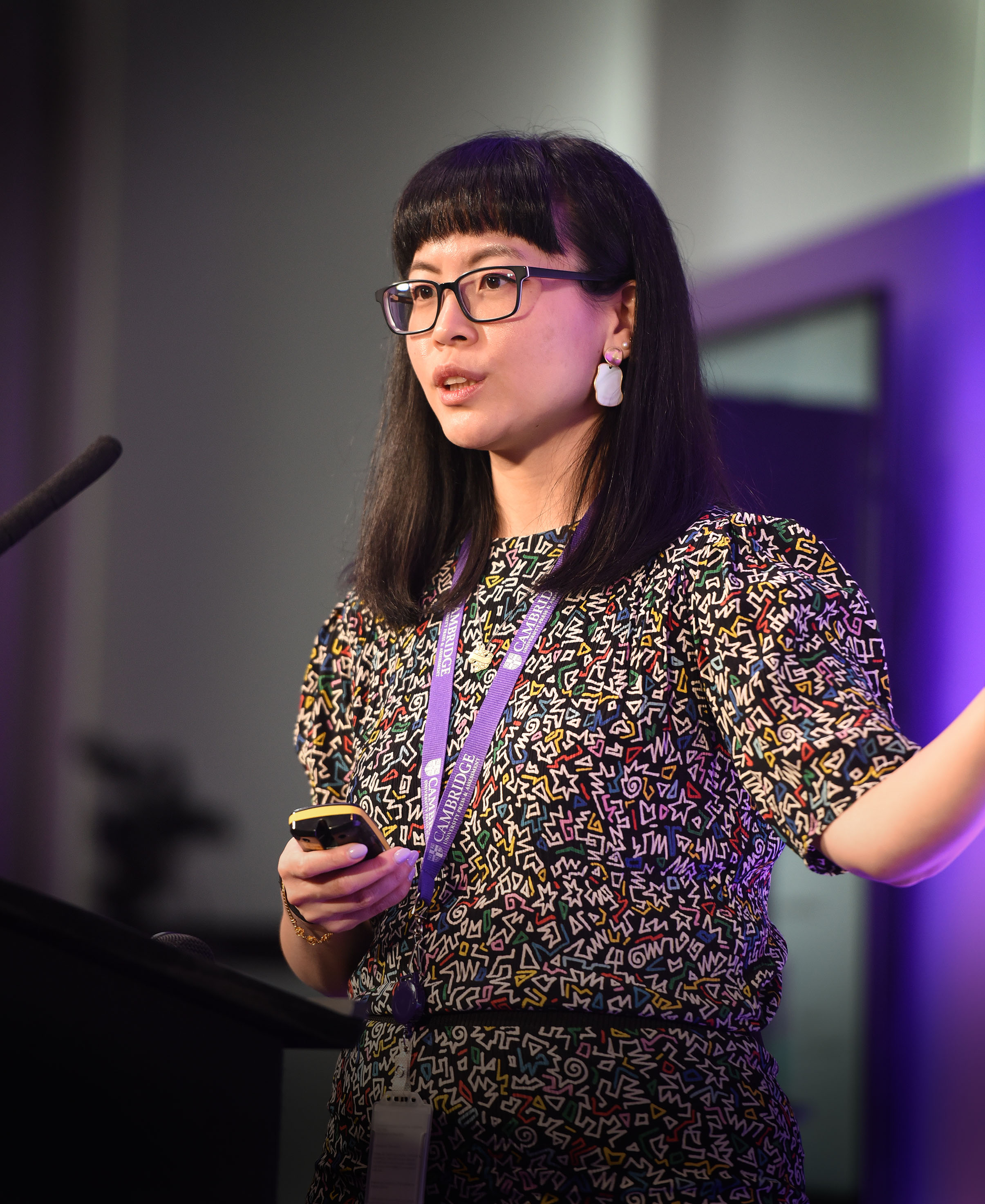 Katherine Chi stands on the main stage next to a lectern holding a remote as she delivers her talk at Digital & Data Day