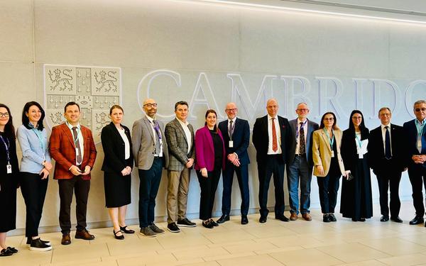 Colleagues gather in front of Cambridge logo