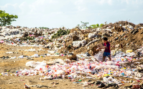 Boy holding cardboard box with Plastic waste surrounding him. Photo by Hermes Rivera on Unsplash