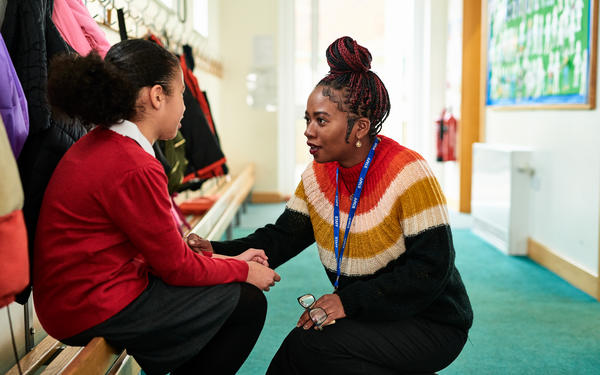 Teacher kneels down to talk to student