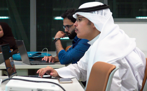 Participants seated at desks using laptops in a classroom setting