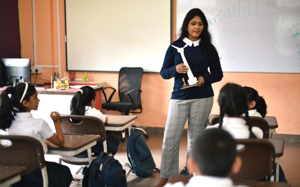 Image of teacher holding a windmill model in front of a classroom
