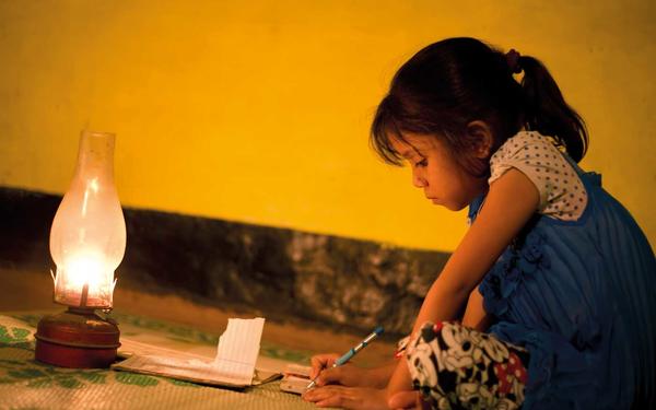 Girl writing beside oil lamp