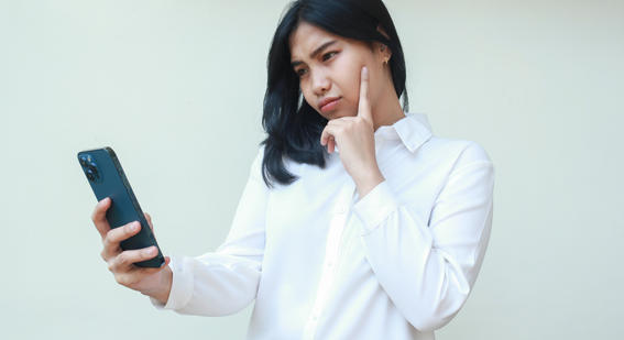 teenage girl looking at mobile phone with finger on chin 