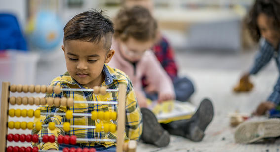 Young child plays with abacus in classroom