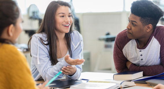 Teen girl smiles as she debates with peers in a classroom