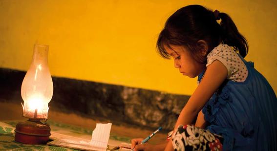 Girl writing beside oil lamp
